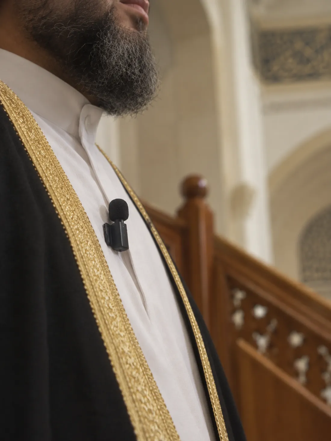 An imam on the minbar with a small wireless microphone clipped to his robe